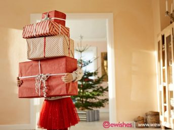 Little girl holding tall stack of christmas presents, standing in living room