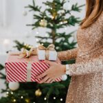 woman in golden glittering dress holding christmas presents