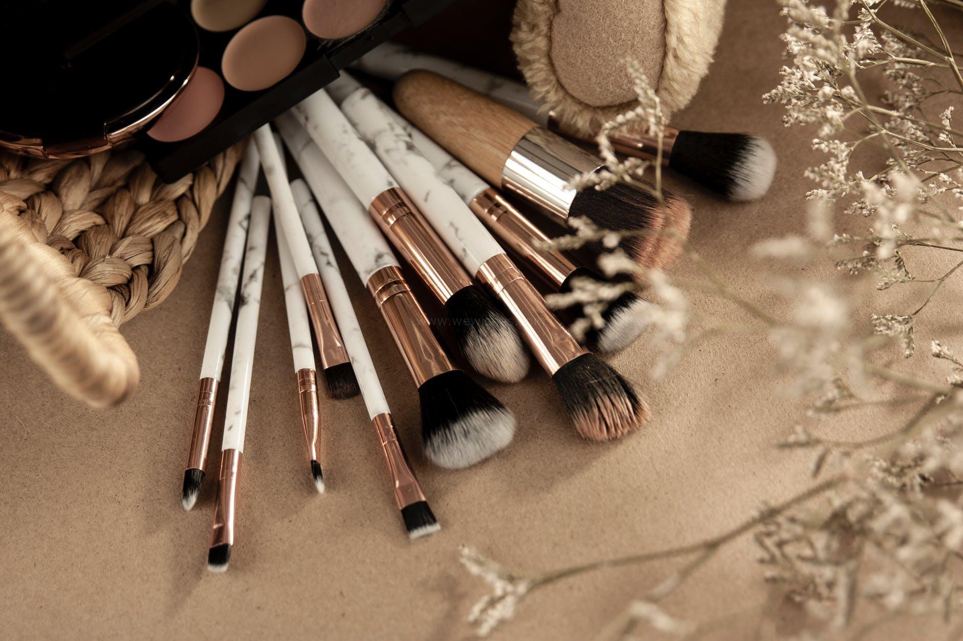 makeup brushes with eyeshadows on beige surface