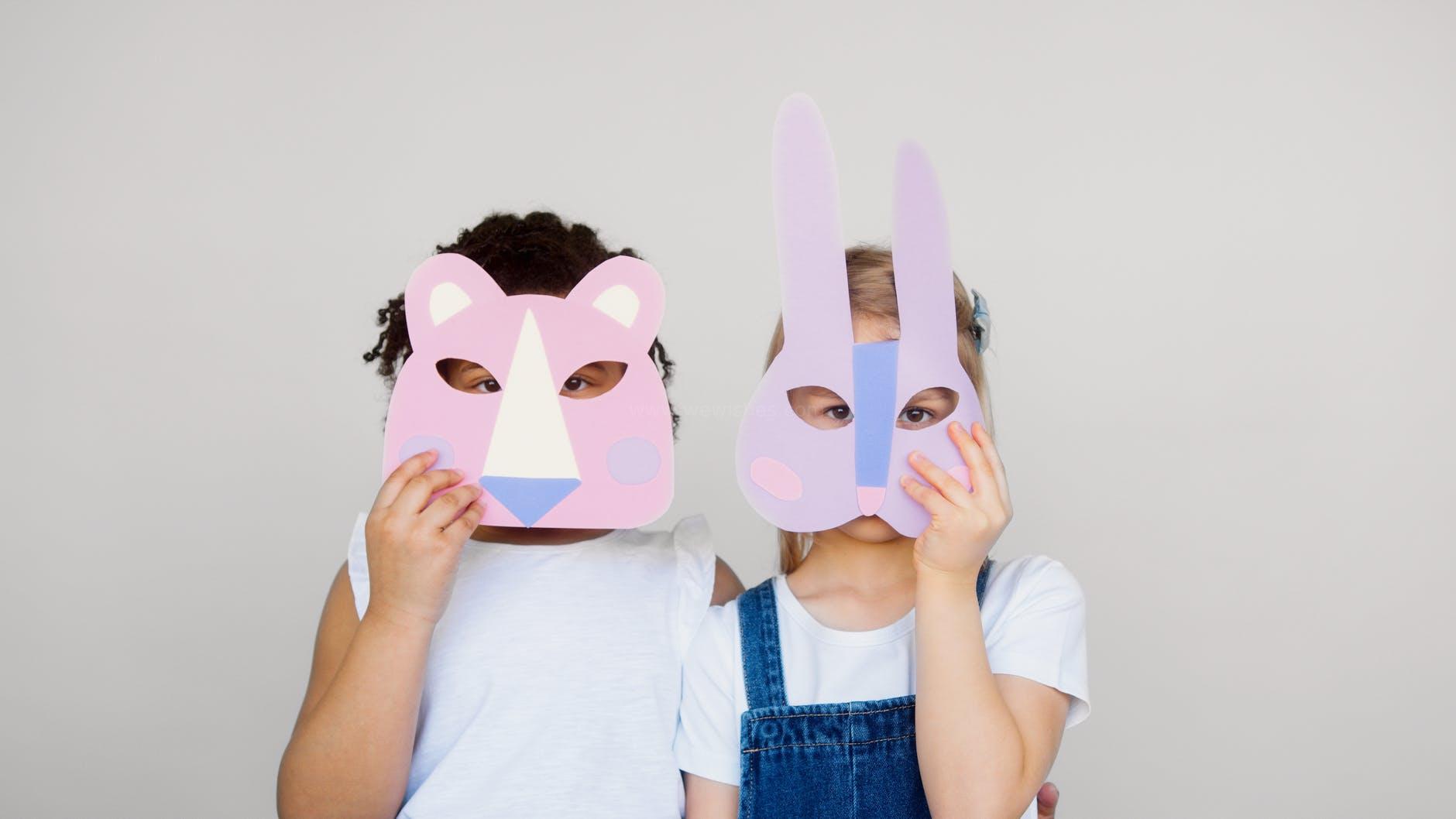 two kids covering their faces with a cutout animal mask
