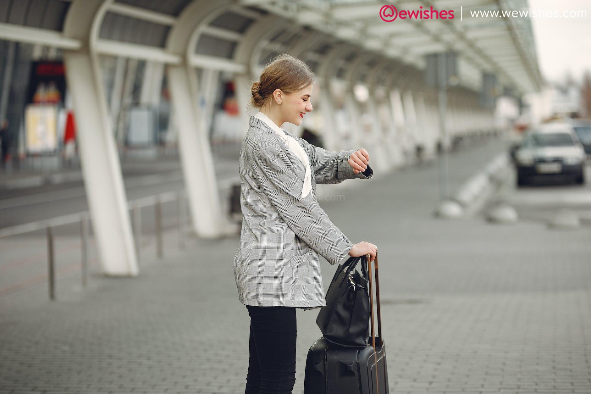 cheerful female manager checking time on wristwatch standing with bags near bus station