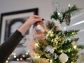 person holding beige bauble near christmas tree